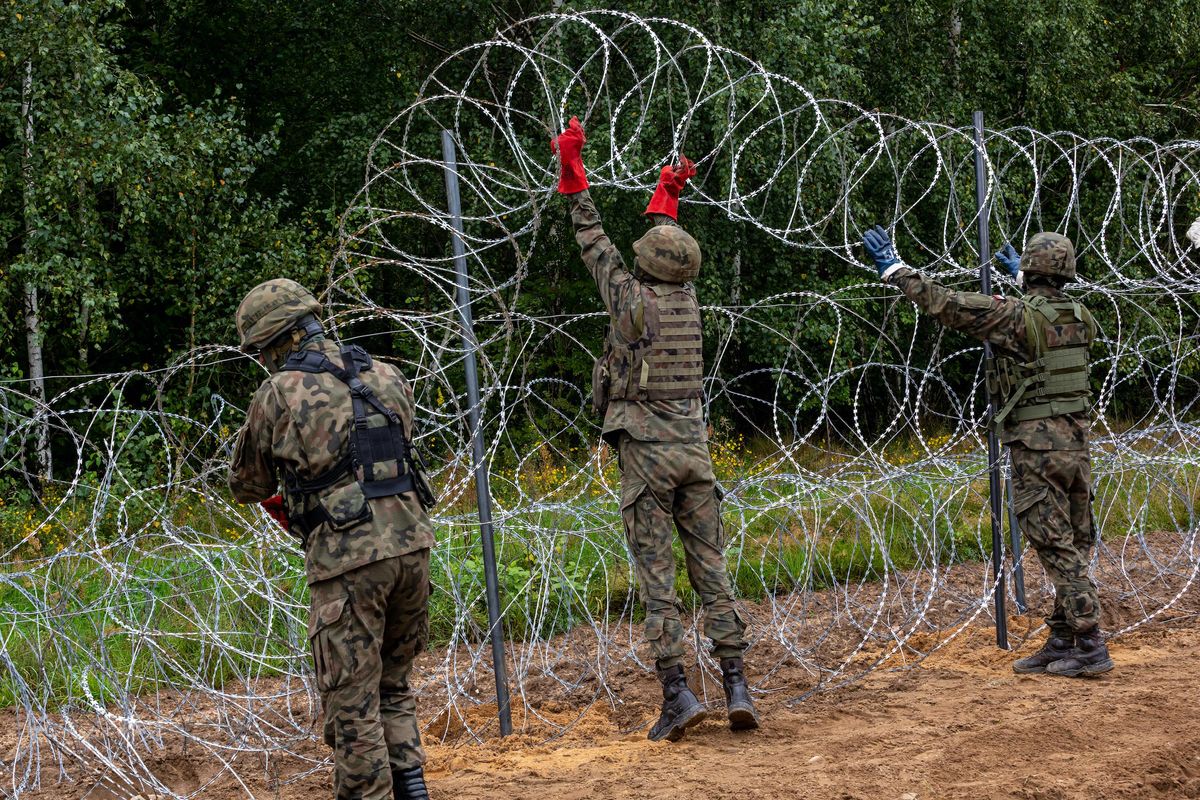 Polish Army Soldiers build a fence with concertina wire at the Belarusian border in order to stop immigrants from entering the country in Krynki, Poland on 27 August, 2021.