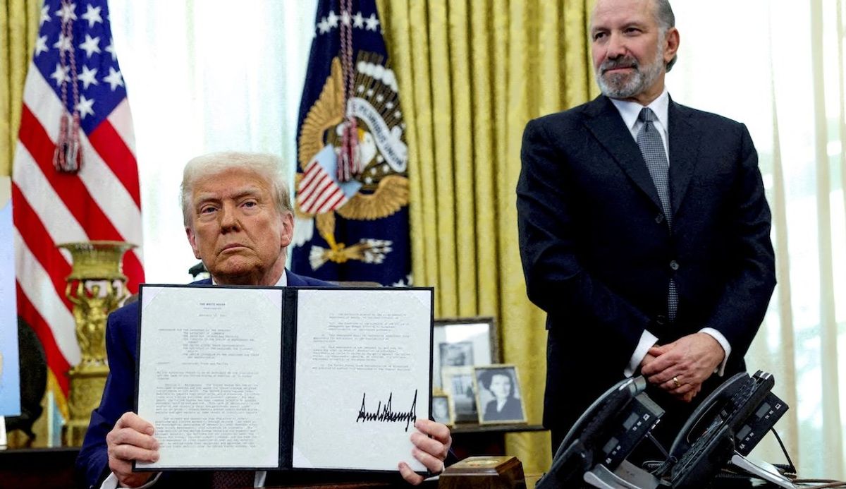 President Donald Trump holds an executive order about tariffs while flanked by Commerce Secretary Howard Lutnick in the Oval Office on Feb. 13, 2025. 
