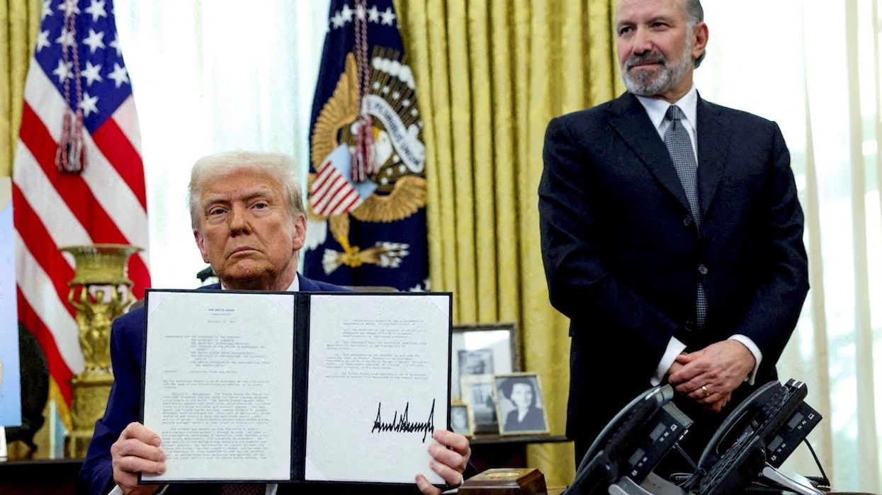 President Donald Trump holds an executive order about tariffs while flanked by Commerce Secretary Howard Lutnick in the Oval Office on Feb. 13, 2025.
