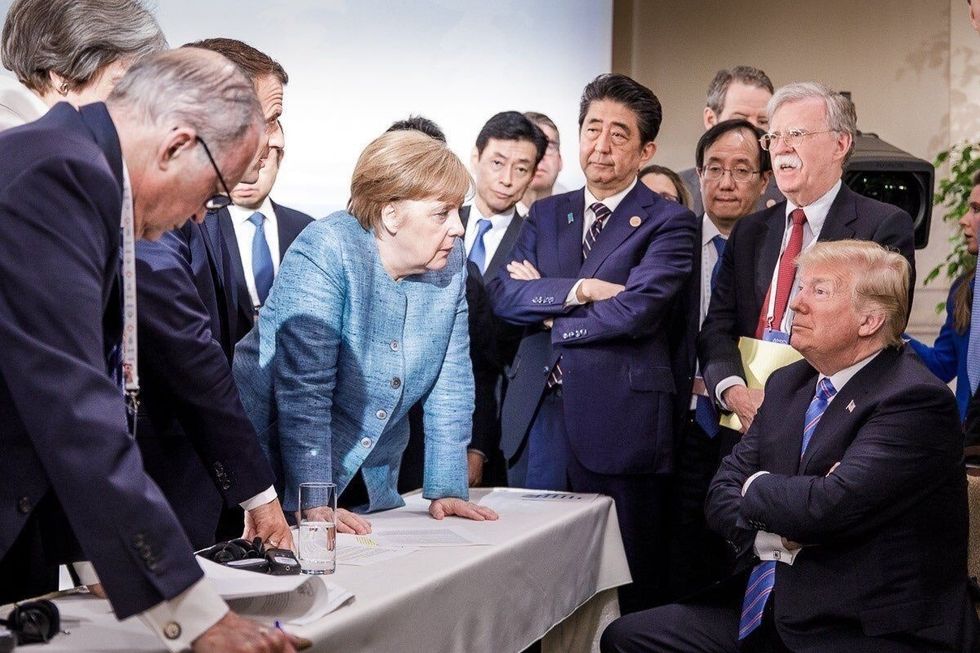 President Donald Trump seated surrounded by foreign leaders including Germany's Angela Merkel, Japan's Shinzo Abe and France's Emmanuel Macron