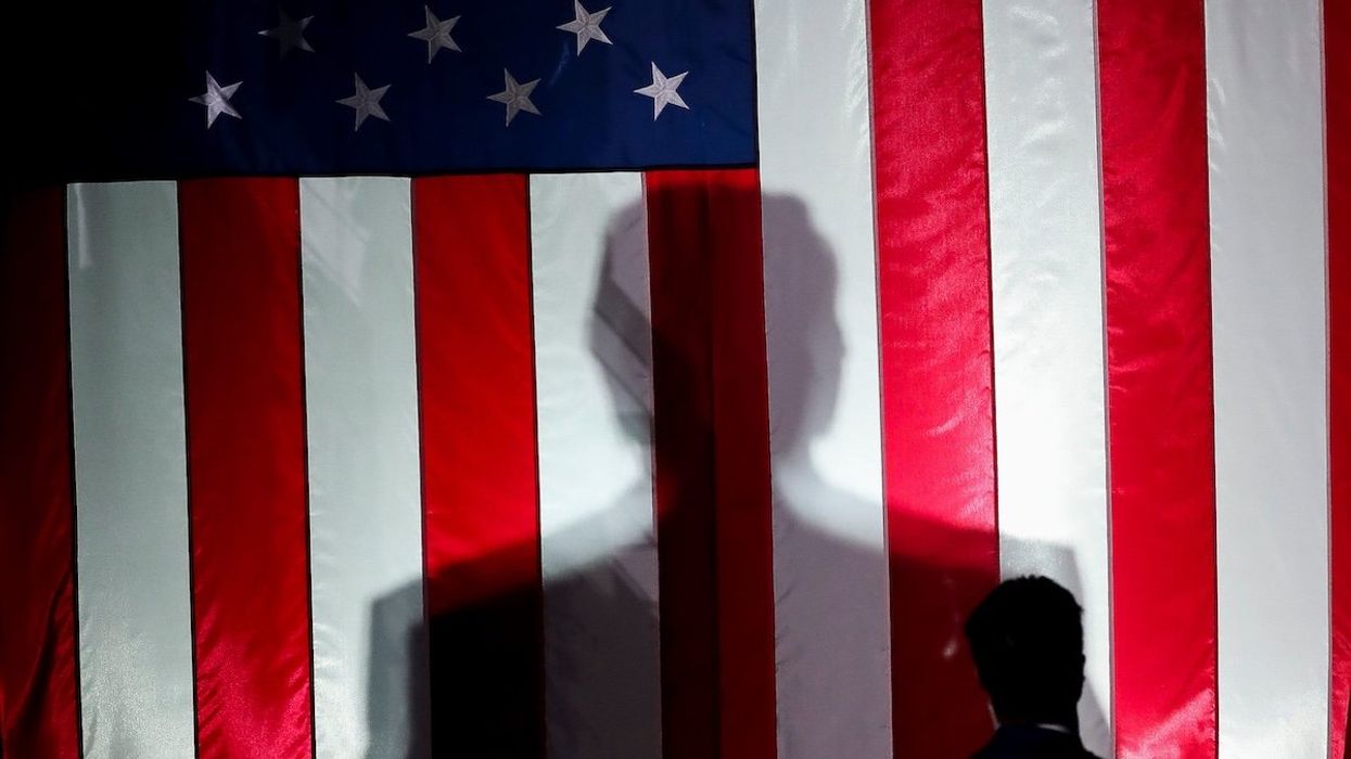 President-elect Donald Trump’s silhouette is seen against a United States flag at a campaign rally in October 2024.