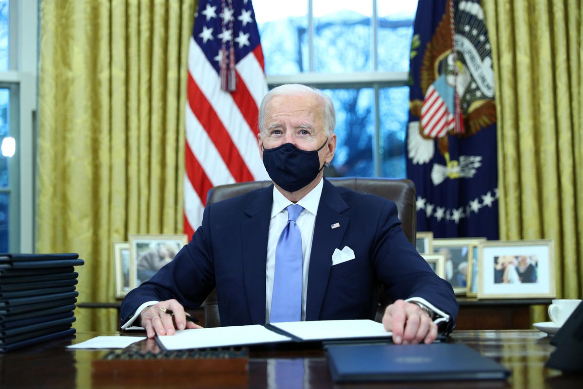 President Joe Biden signs executive actions in the Oval Office after his inauguration. REUTERS/Tom Brenner