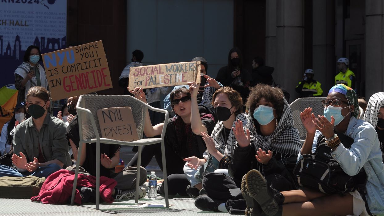 Pro-Palestine protesters hold placards expressing their opinion as they participate in a sit-in demonstration at New York University.