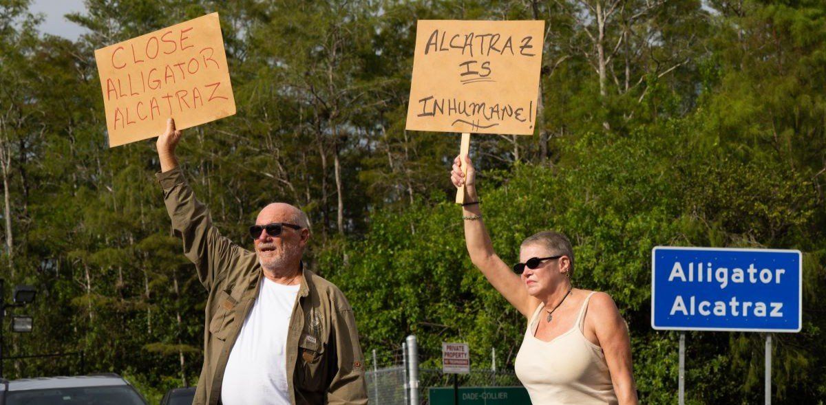 Protesters line the street outside Alligator Alcatraz in Ochopee, Florida, holding signs during a vigil on Aug. 10, 2025.