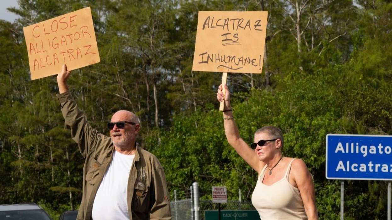 Protesters line the street outside Alligator Alcatraz in Ochopee, Florida, holding signs during a vigil on Aug. 10, 2025.