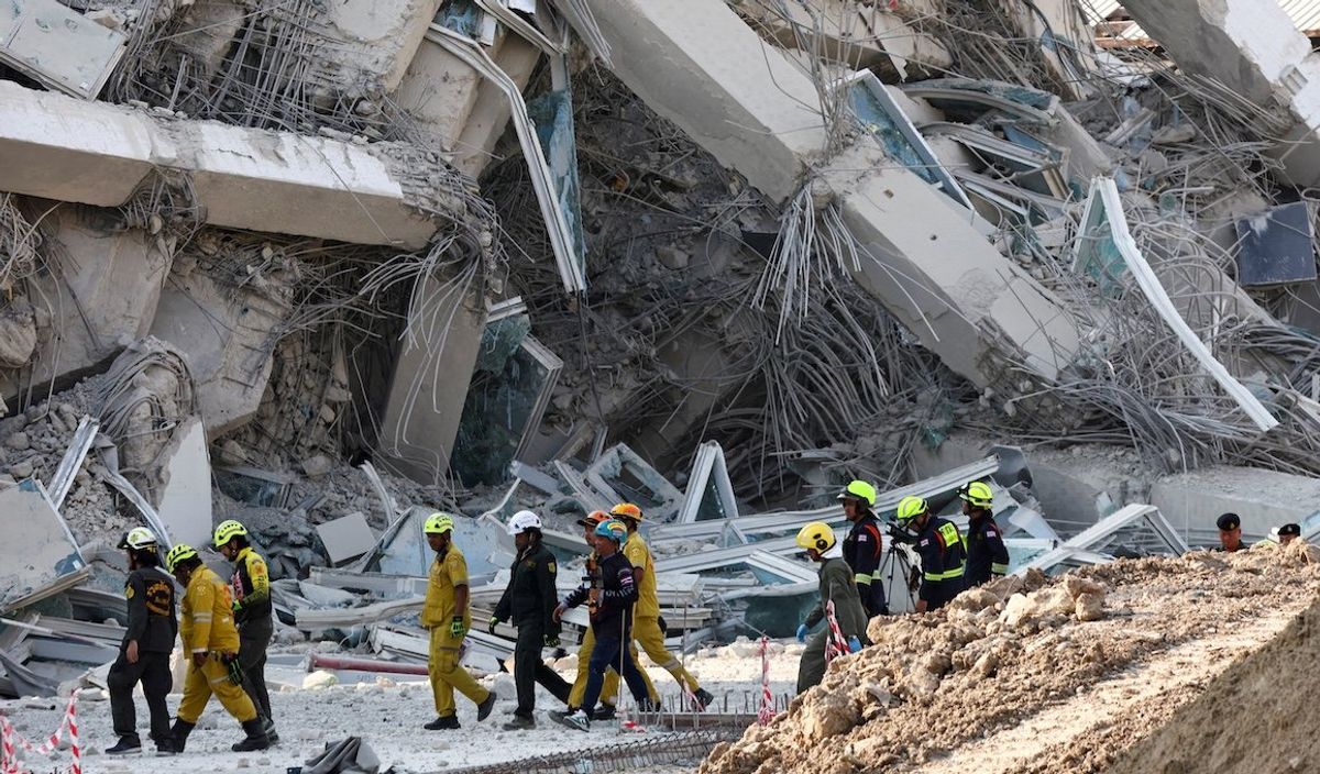 ​Rescue personnel walk near a building that collapsed after a strong earthquake struck central Myanmar on Friday, March 28, 2025.