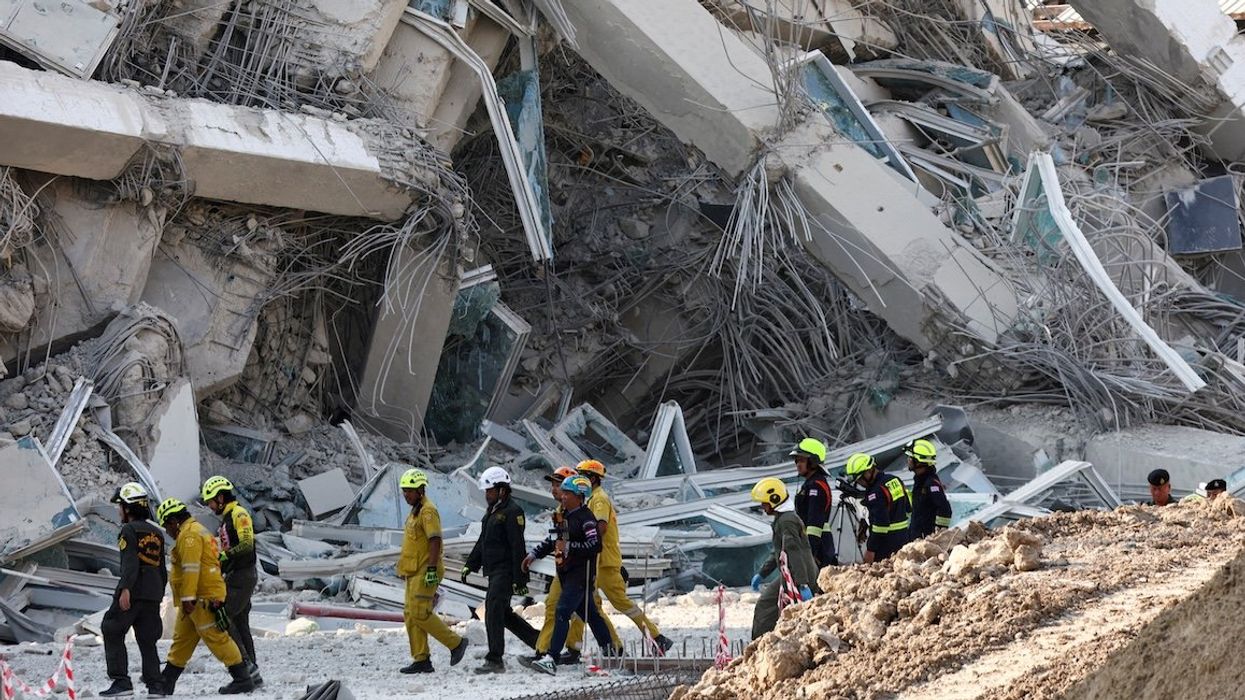 Rescue personnel walk near a building that collapsed after a strong earthquake struck central Myanmar on Friday, March 28, 2025.