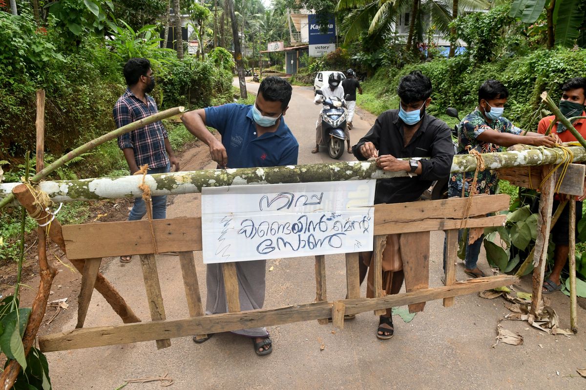 Residents fix a sign reading "Nipah containment zone" on a barricade