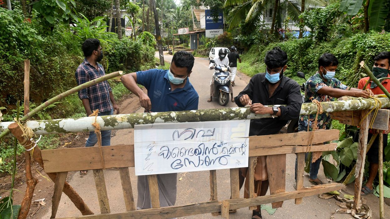 Residents fix a sign reading "Nipah containment zone" on a barricade