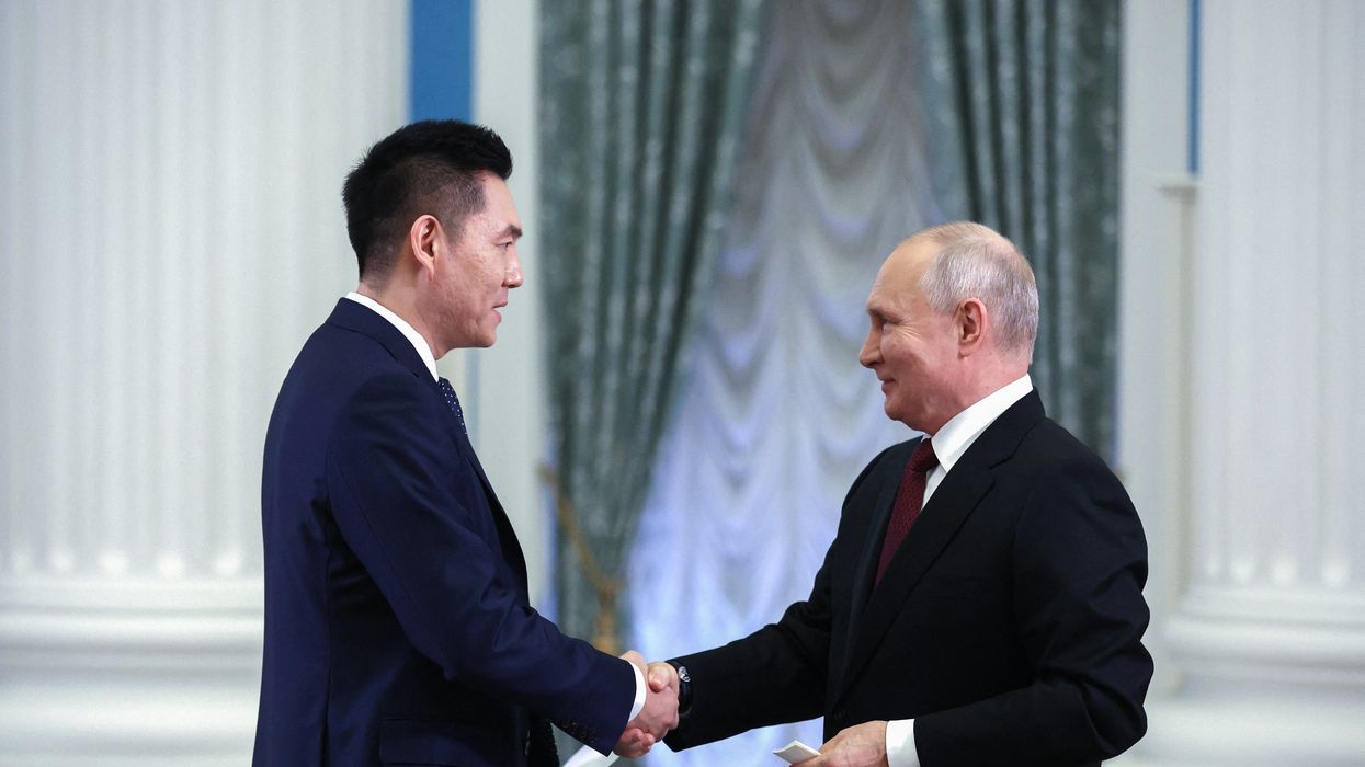 Russian President Vladimir Putin shakes hands with China Media Group anchor Wang Guan