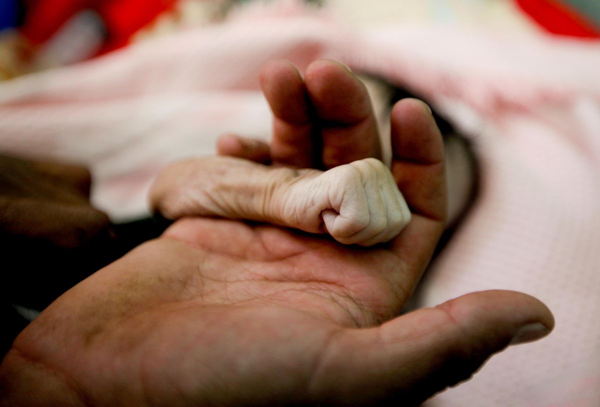 Saleh Hassan al-Faqeh holds the hand of his four-month-old daughter, Hajar, who died at the malnutrition ward of al-Sabeen hospital in Sanaa, Yemen, November 15, 2018.