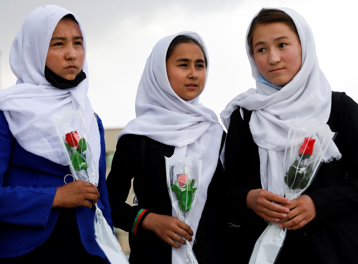 Schoolgirls hold flowers as they arrive to visit students who were injured in a car bomb blast outside a school, at a hospital in Kabul, Afghanistan May 10, 2021.