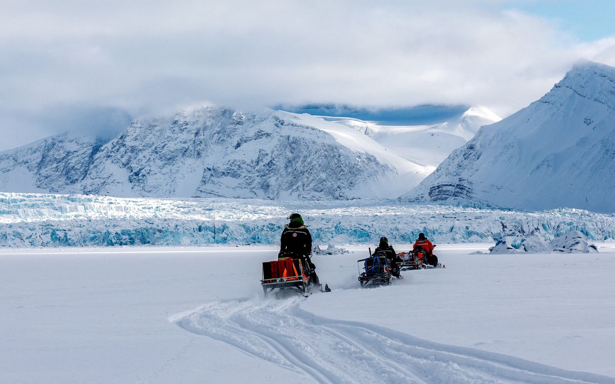 Scientists ride their snowmobiles near Kronebreen glacier through the arctic landscape in Norway.