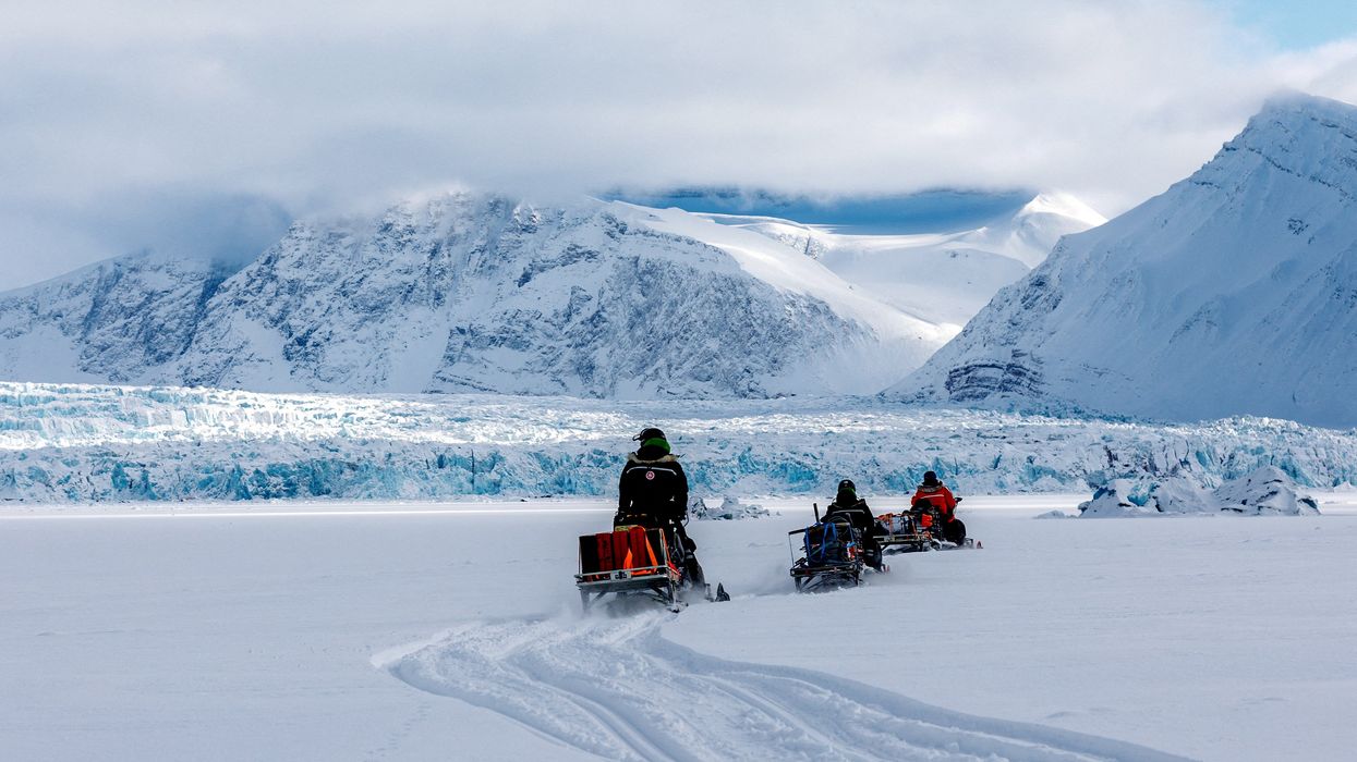 Scientists ride their snowmobiles near Kronebreen glacier through the arctic landscape in Norway.
