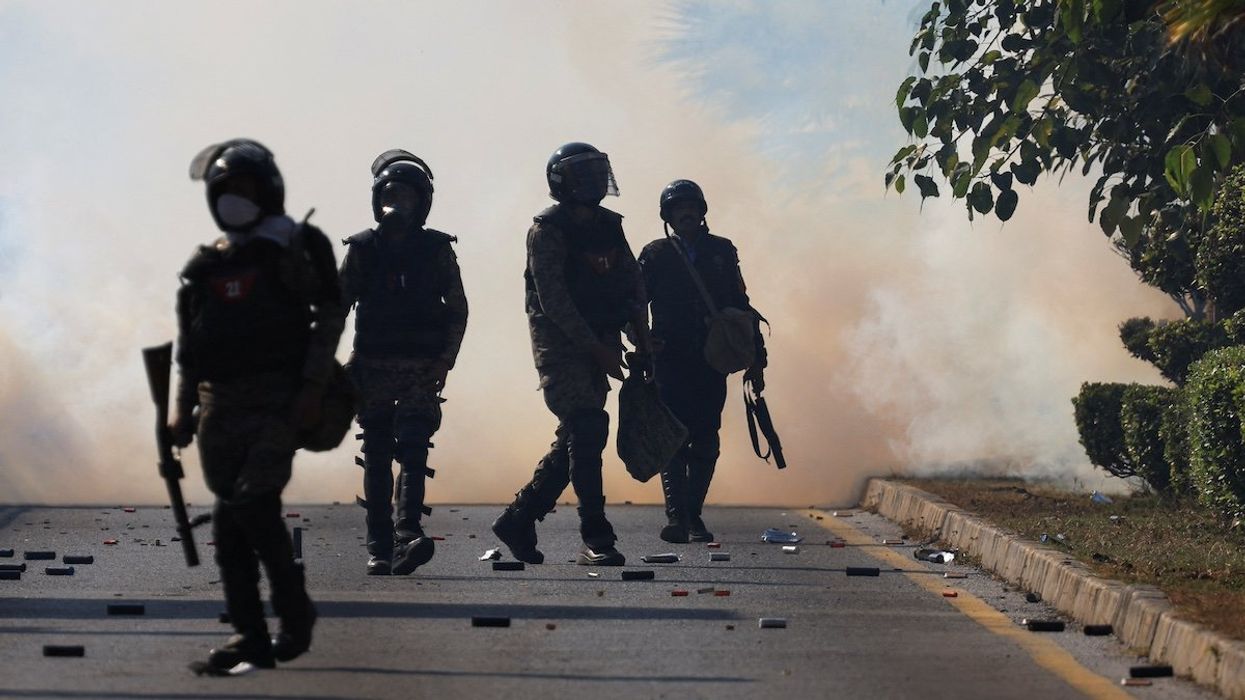 Security force personnel walk as smoke billows from tear gas shells fired to prevent an anti-government protest by supporters of the former Pakistani Prime Minister Imran Khan's party Pakistan Tehreek-e-Insaf (PTI) demanding the release of Khan, in Islamabad, Pakistan, November 26, 2024