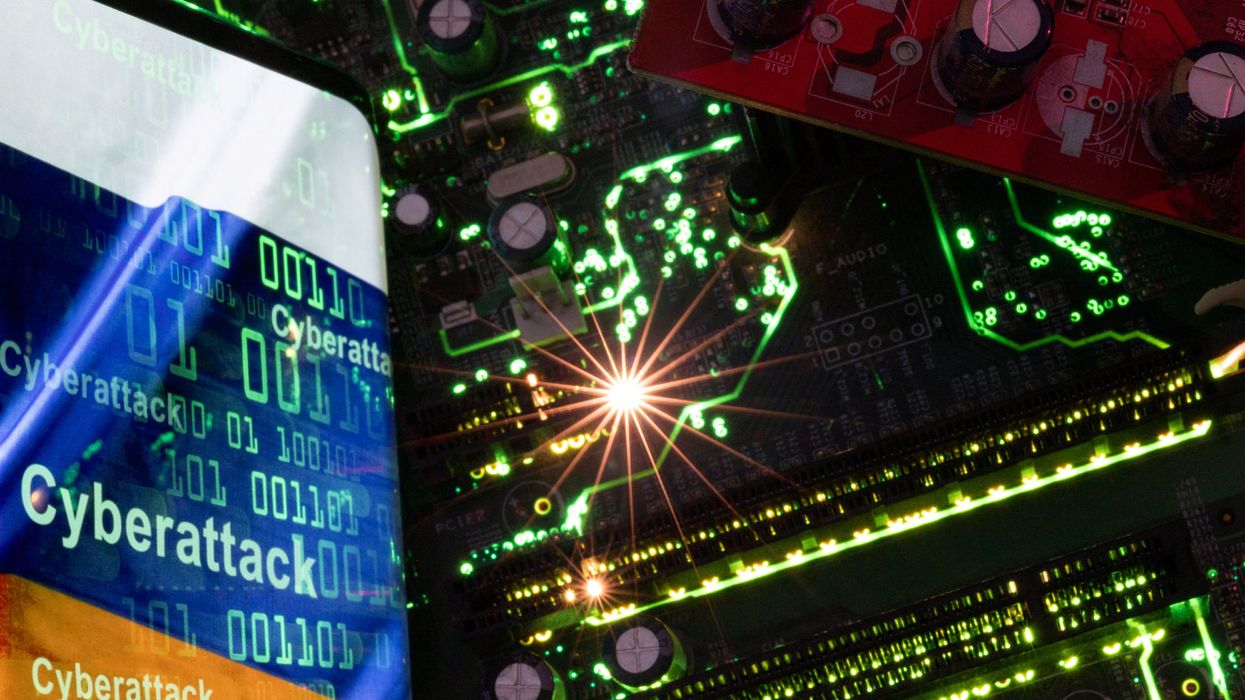 Smartphone with a displayed Russian flag with the word "Cyberattack" and binary codes over it is placed on a computer motherboard in this illustration.