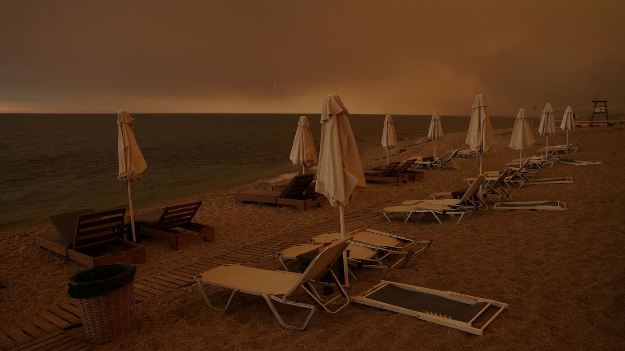 Smoke rises next to sunbeams and umbrellas as a wildfire burns, at the beach of the village of Dikella in the region of Evros, Greece.