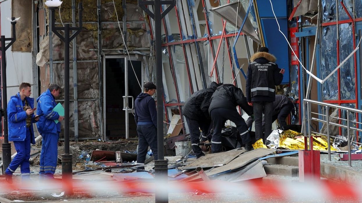 Specialists tend to the body of a victim outside a damaged shopping center hit by a missile strike in Belgorod, Russia, on Feb. 15, 2024.