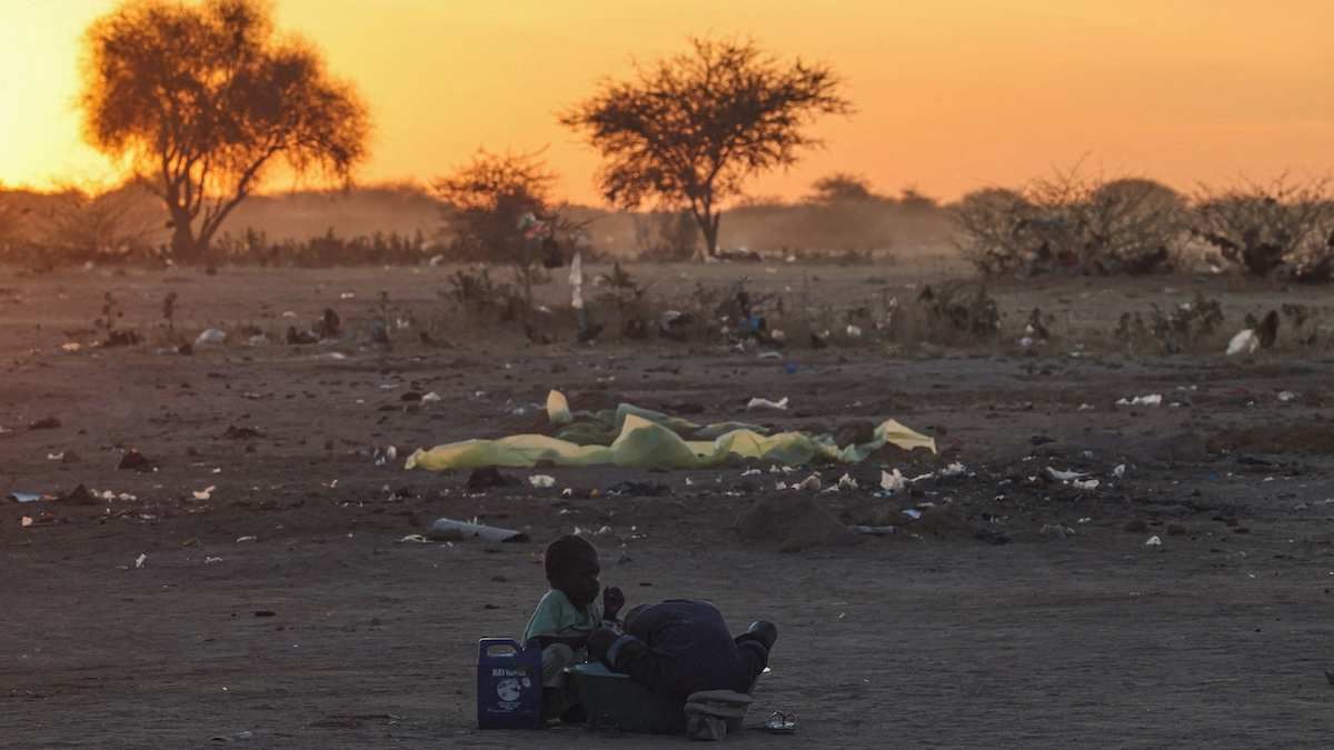 ​Sudanese brothers, refugees from el-Fasher, wash clothes at sunset outside the Tine transit camp in eastern Chad, on November 22, 2025.