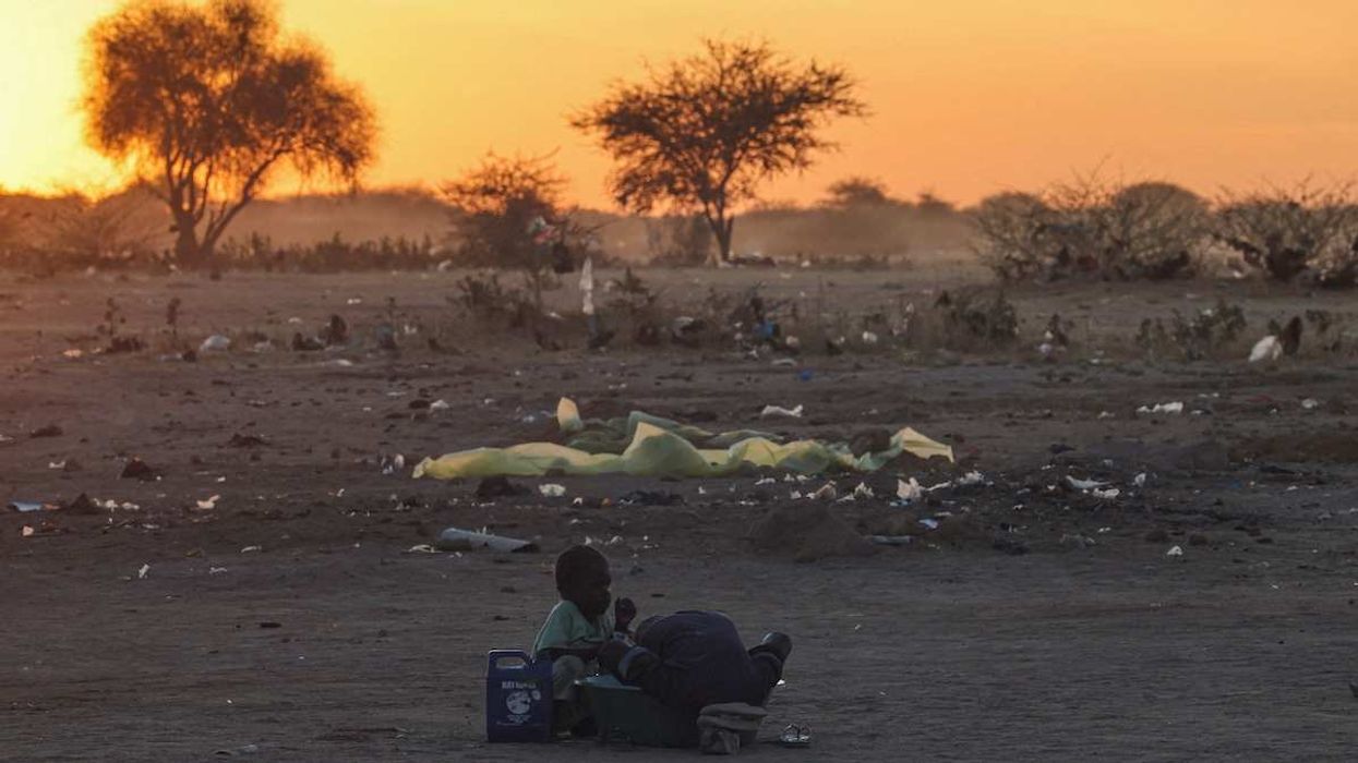 Sudanese brothers, refugees from el-Fasher, wash clothes at sunset outside the Tine transit camp in eastern Chad, on November 22, 2025.