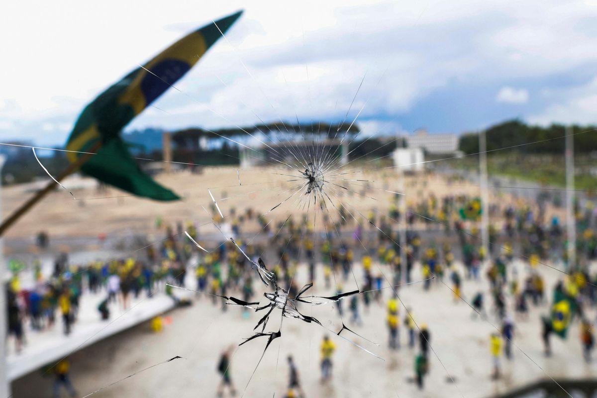 Supporters of Brazil's former President Jair Bolsonaro are pictured through a broken glass as they demonstrate against President Luiz Inacio Lula da Silva outside the Congress building in Brasilia.