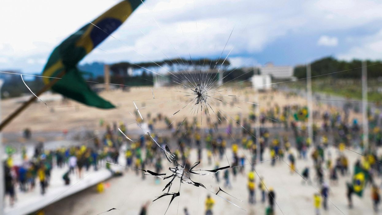 Supporters of Brazil's former President Jair Bolsonaro are pictured through a broken glass as they demonstrate against President Luiz Inacio Lula da Silva outside the Congress building in Brasilia.