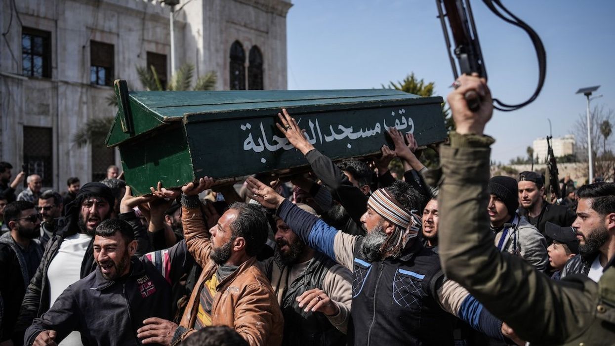 Syrian fighters and civilians carry the coffin of a member of the Syrian security forces during his funeral in Hama province after he and 11 other colleagues were killed in an ambush by groups loyal to the ousted President Bashar al-Assad in Latakia.