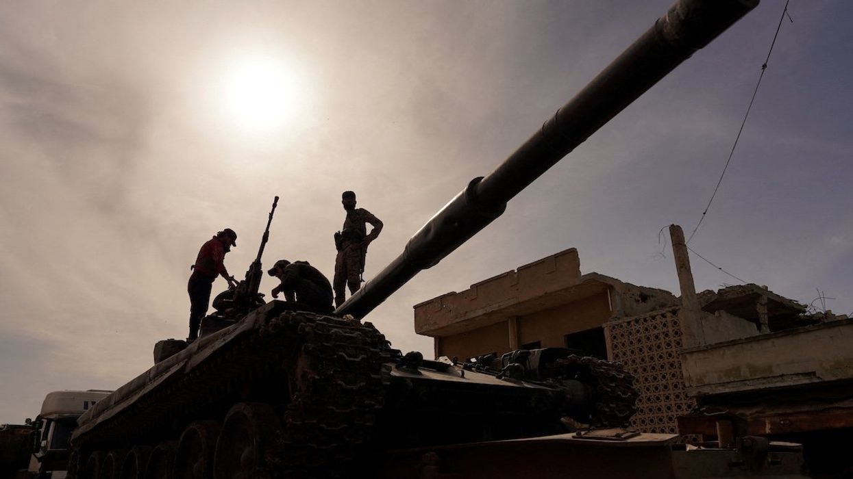 Syrian troops sit atop a tank as they head toward the Syrian-Lebanese border following clashes with Lebanese soldiers and armed groups, in Qusayr, Syria, March 17, 2025.