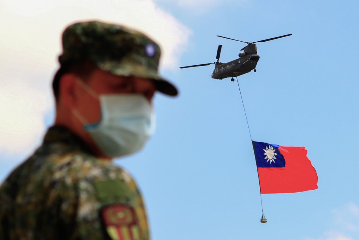 Taiwanese soldiers stand guard as a Chinook Helicopter carrying a tremendous Taiwan flag flies over a military camp, as part of a rehearsal for the flyby performance for Taiwan’s Double-Ten National Day Celebration, amid rising tensions between Beijing and Taipei and threats from China, in Taoyuan, Taiwan 28 September 2021.