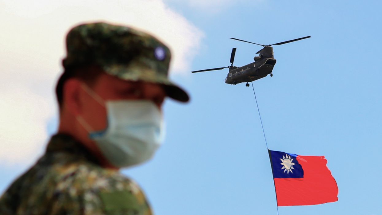 Taiwanese soldiers stand guard as a Chinook Helicopter carrying a tremendous Taiwan flag flies over a military camp, as part of a rehearsal for the flyby performance for Taiwan’s Double-Ten National Day Celebration, amid rising tensions between Beijing and Taipei and threats from China, in Taoyuan, Taiwan 28 September 2021.