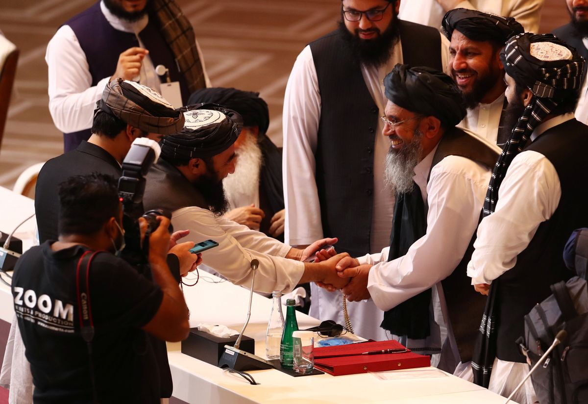 Taliban delegates shake hands during talks between the Afghan government and Taliban insurgents in Doha, Qatar