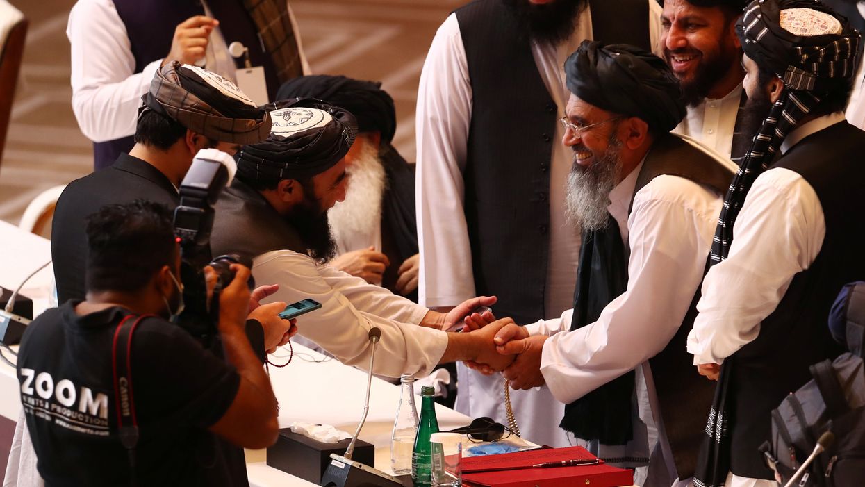 Taliban delegates shake hands during talks between the Afghan government and Taliban insurgents in Doha, Qatar