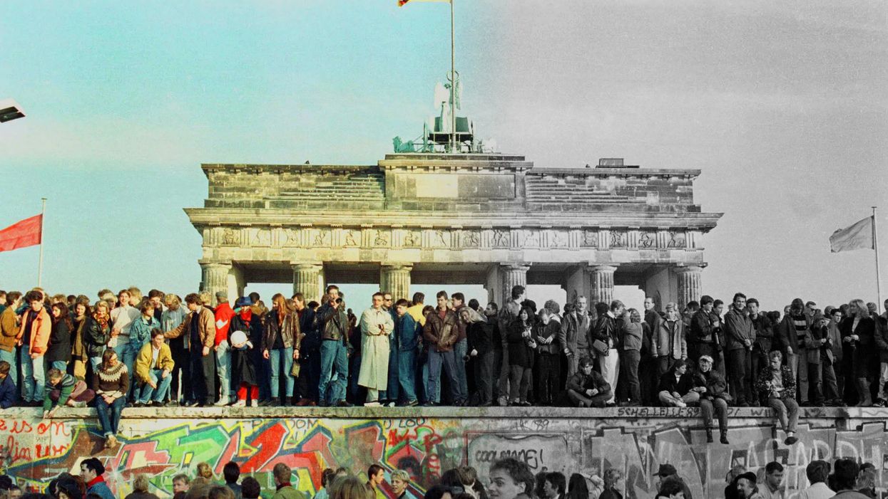 The Brandenburg Gate with a German flag during the period of reunification in Berlin, Germany