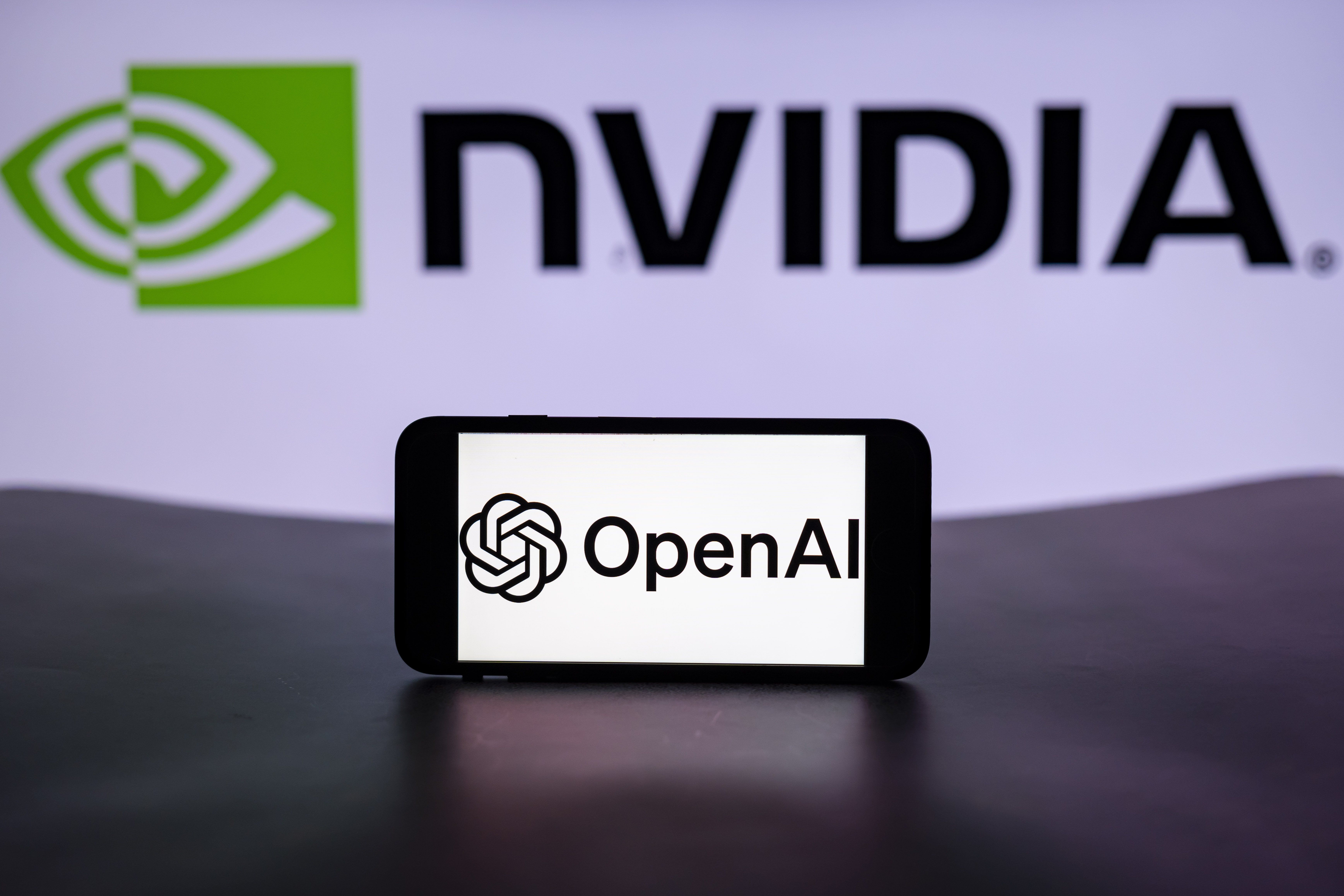 The logo of OpenAI is seen displayed on a mobile phone screen with the Nvidia logo in the background. 
