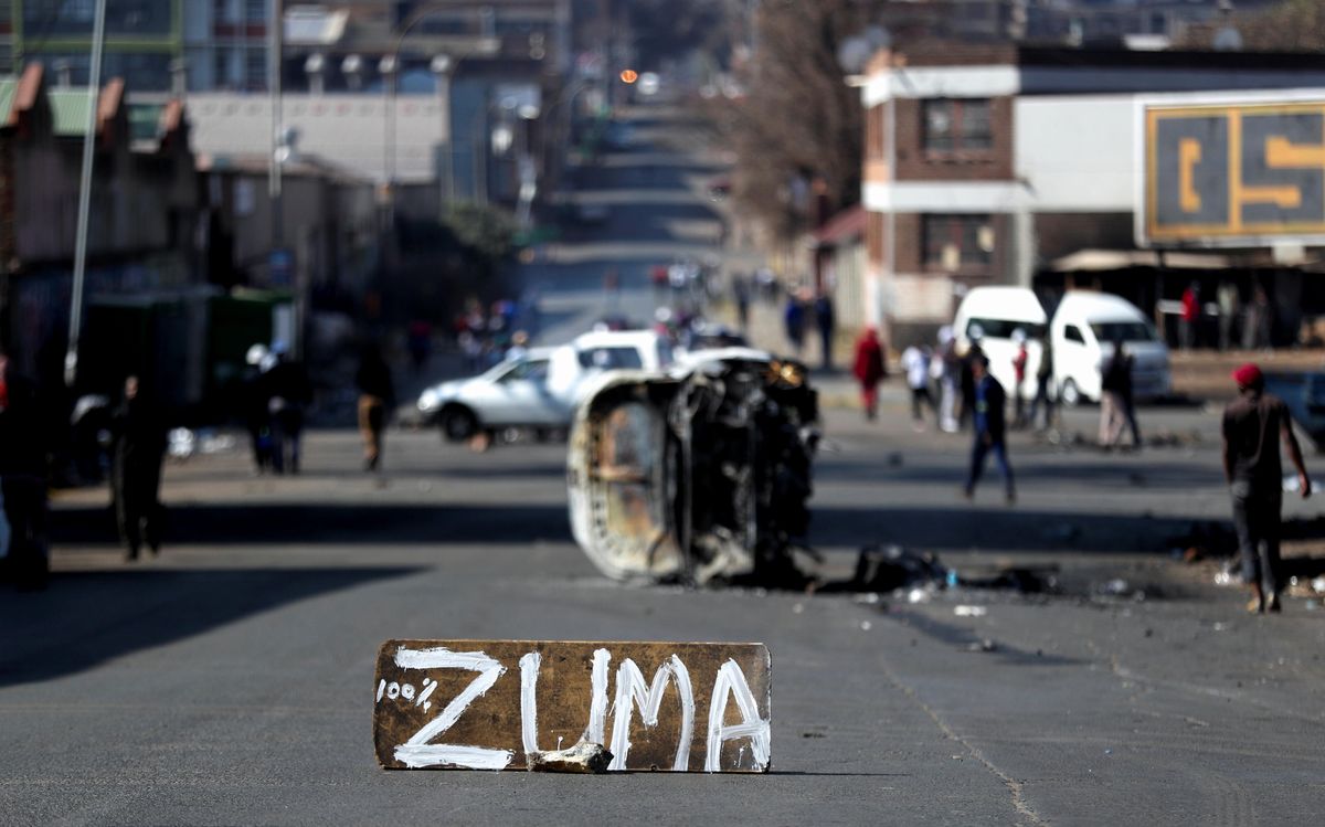 The remains of a burnt car and a sign block the road after stick-wielding protesters marched through the streets, as violence following the jailing of former South African President Jacob Zuma spread to the country's main economic hub in Johannesburg, South Africa, July 11, 2021
