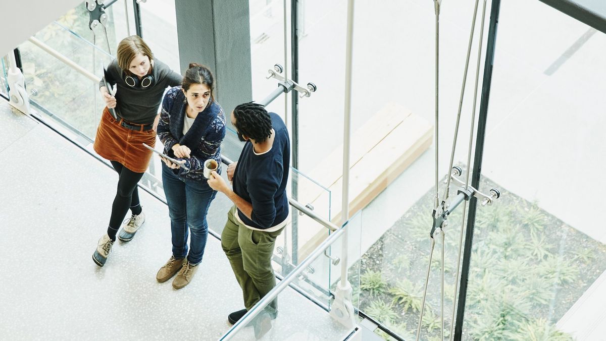 Three people in a workplace standing and talking