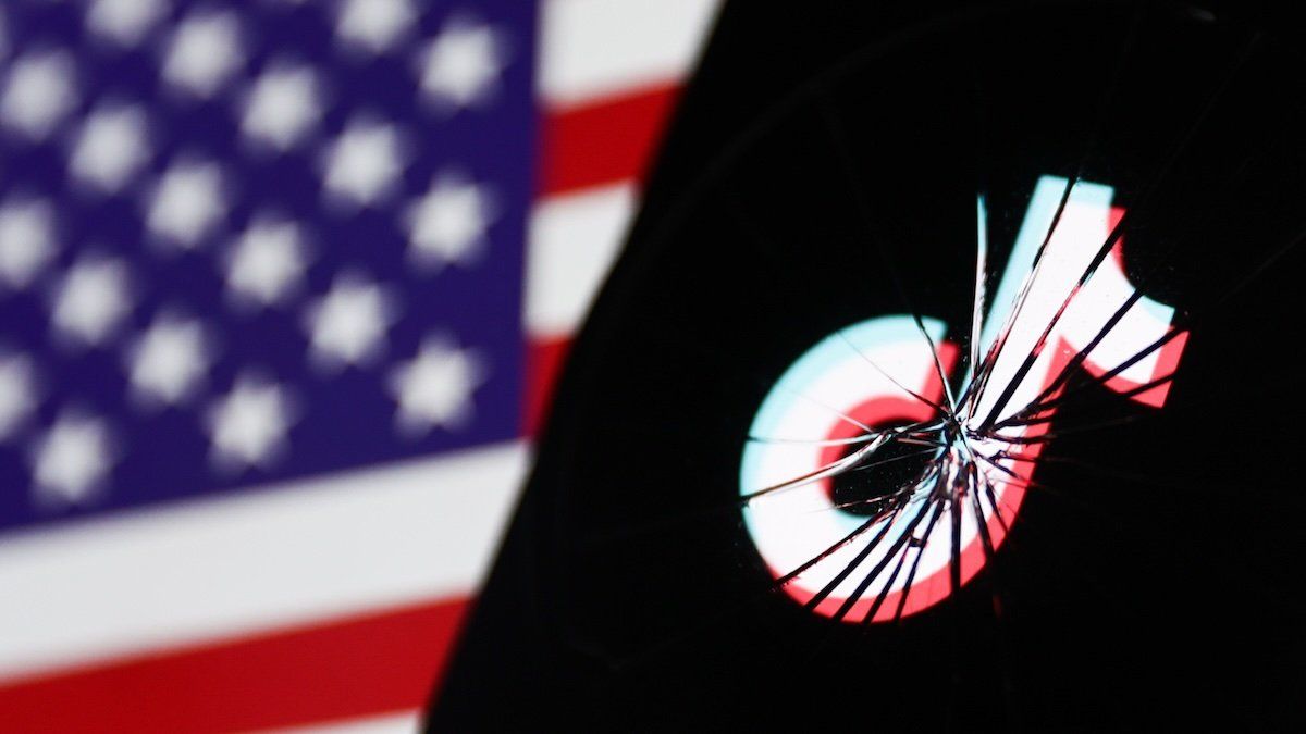 TikTok logo displayed on a phone screen is seen through the broken glass with American flag displayed on a screen in the background in this illustration photo taken in Krakow, Poland on April 24, 2024.
