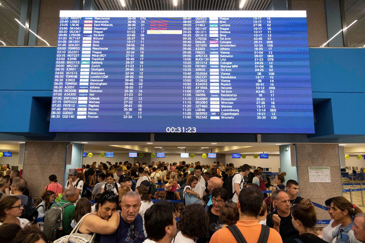 Tourists line up at check-in counters as they wait for departing planes at the airport after being evacuated from wildfires on the Greek island of Rhodes.