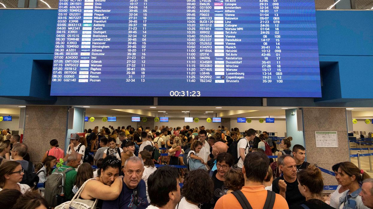 Tourists line up at check-in counters as they wait for departing planes at the airport after being evacuated from wildfires on the Greek island of Rhodes.