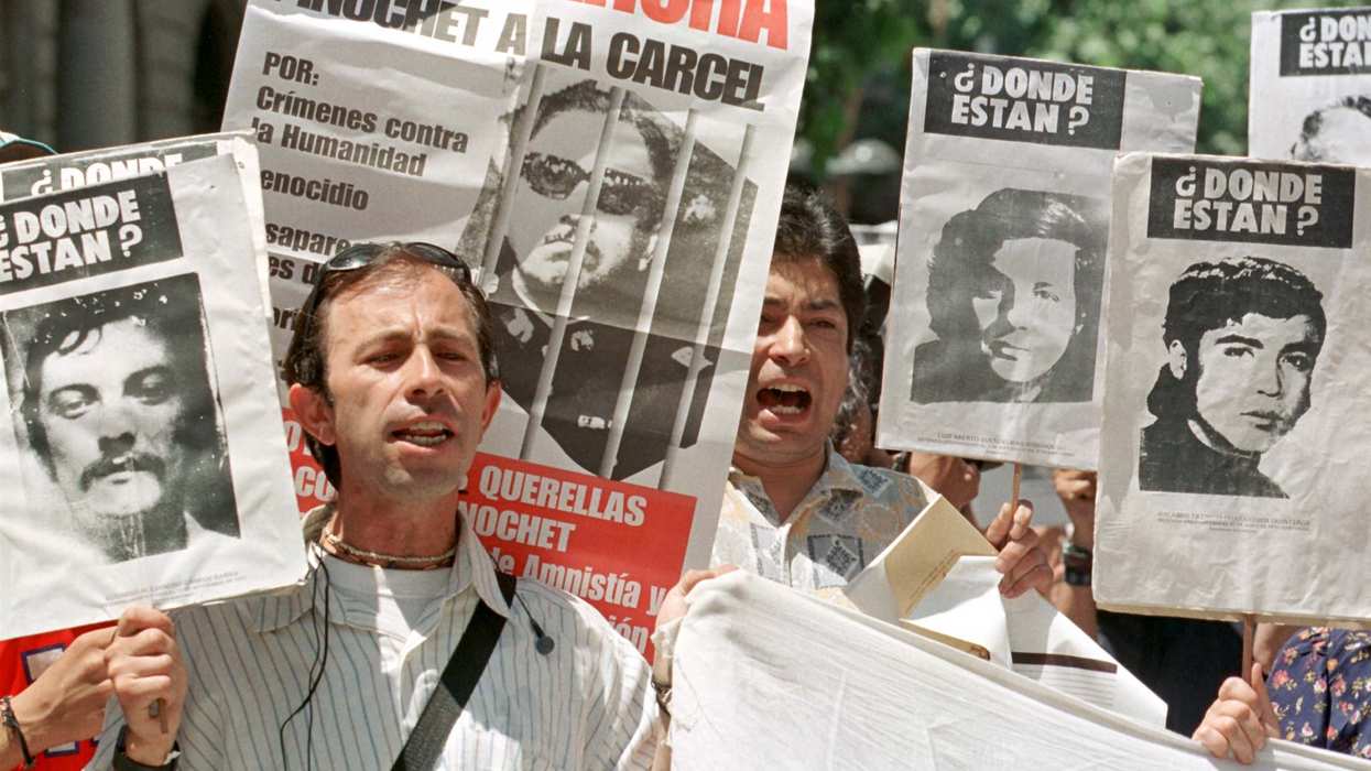 Two Chilean men yell slogans against former leader Gen. Augusto Pinochet while holding onto pictures of people allegedly disappeared during the dictatorship.