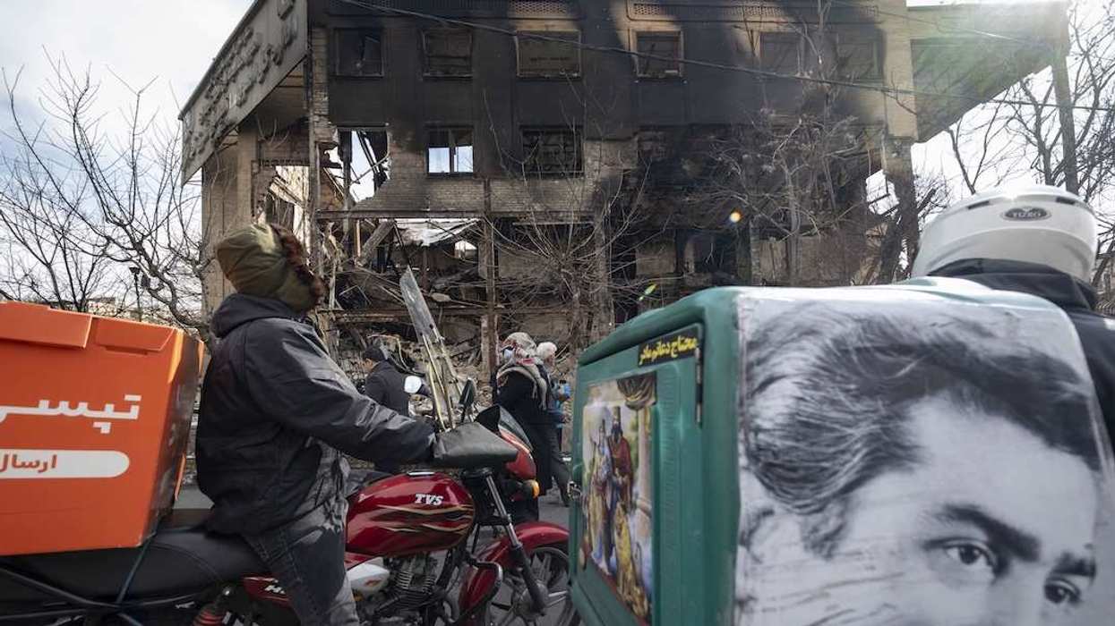 Two Iranian motorcyclists stop in front of the burned East Tehran General Directorate of Tax Affairs headquarters in Tehran, Iran, on January 21, 2026.