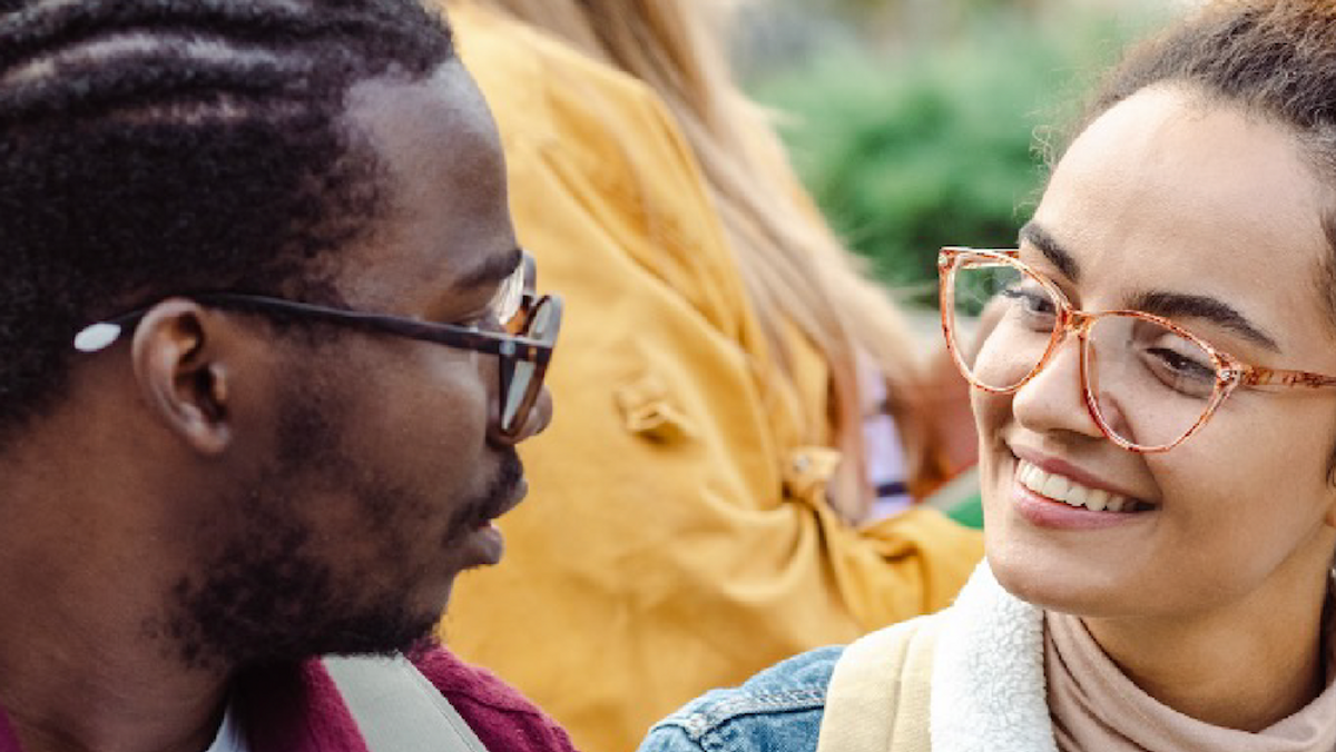 Two students with glasses smile at each other