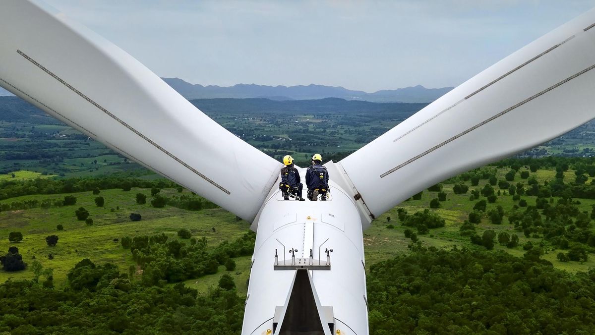 Two workers on a wind turbine look at a green landscape | The Bank of America Institute