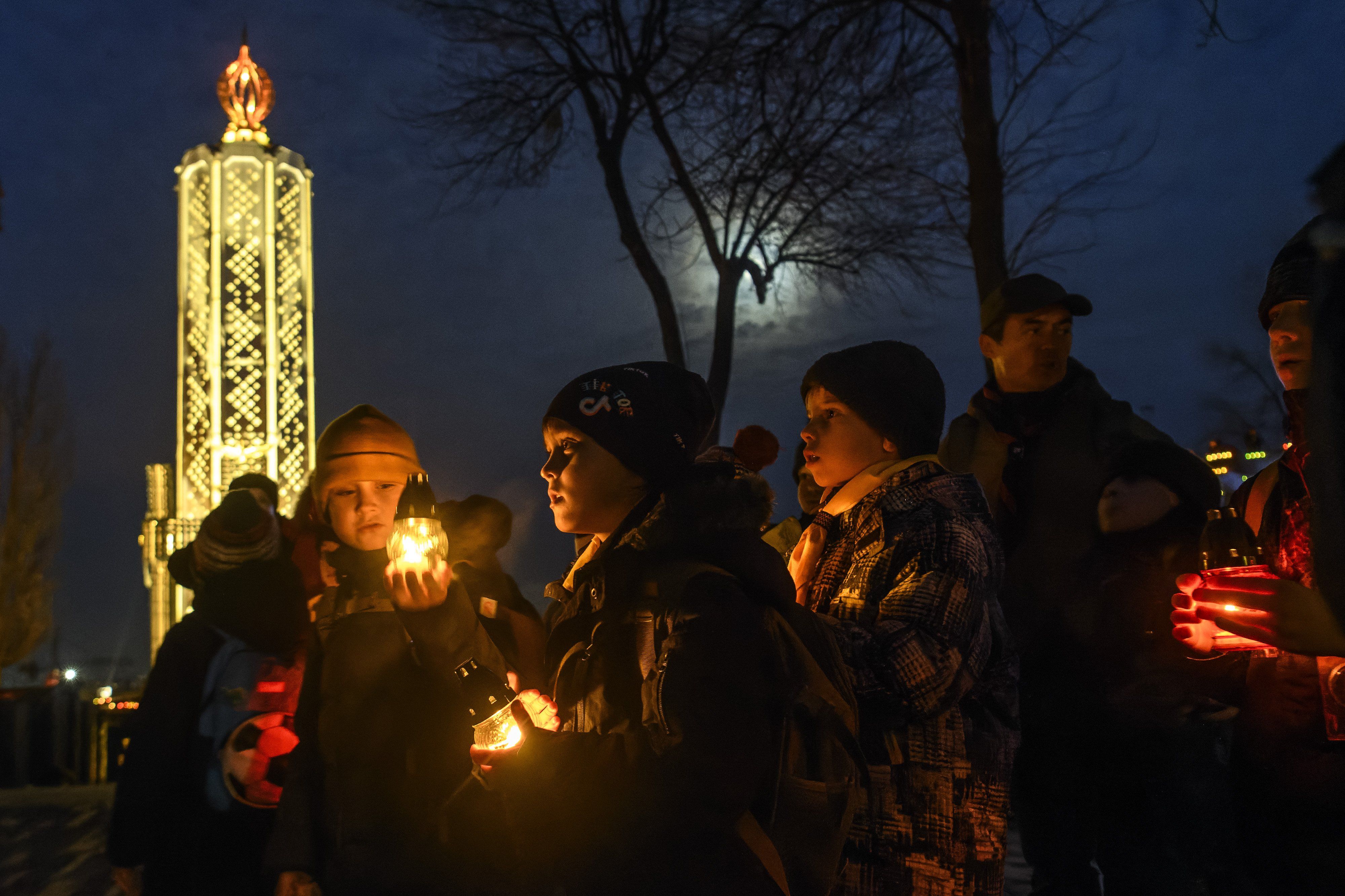 Ukrainians visit a monument to Holodomor victims during a commemoration ceremony marking the 90th anniversary of the famine of 1932-33, against a backdrop of Russian drones attacking Kyiv.