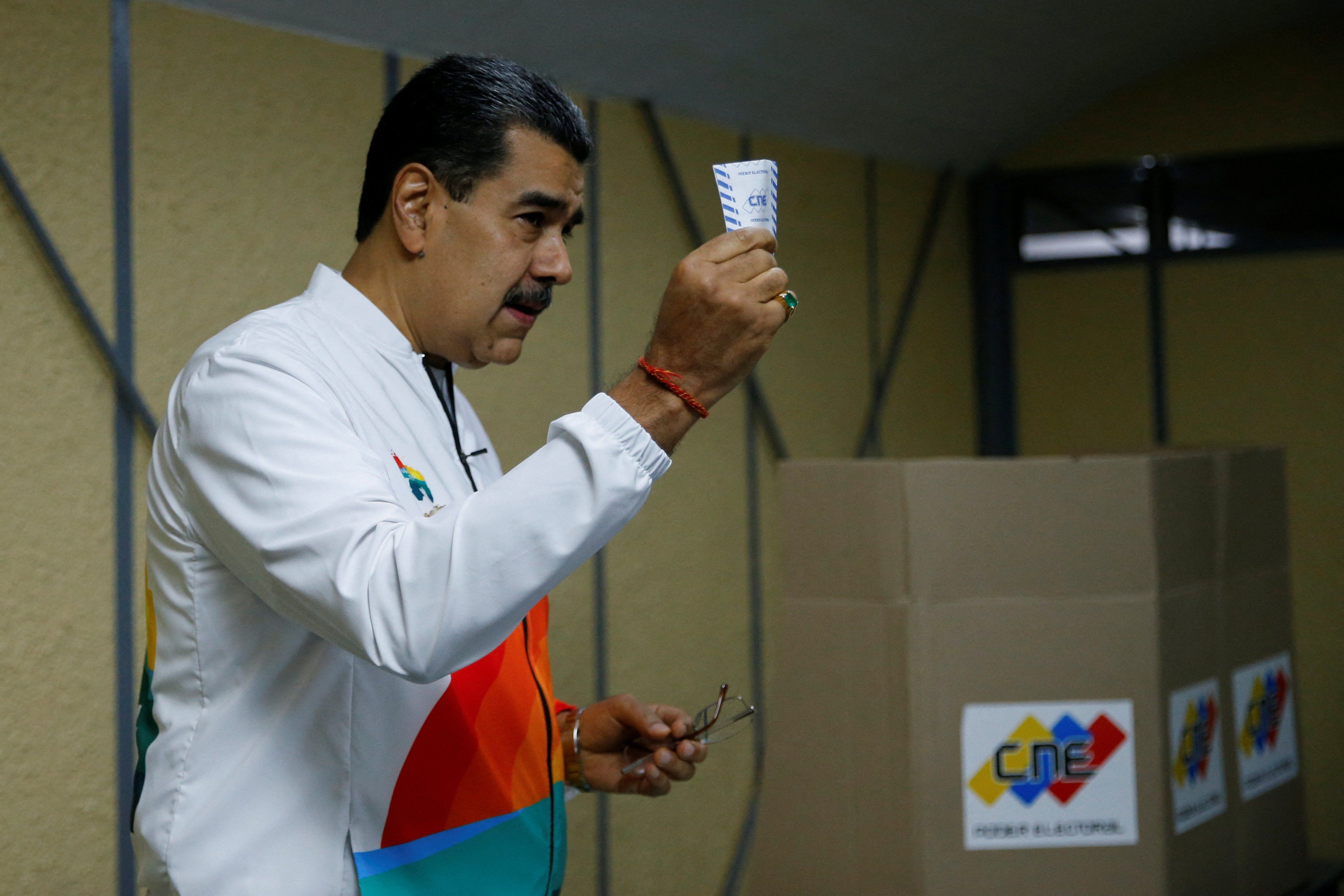​Venezuela's President Nicolas Maduro shows his ballot during a referendum over Venezuela's rights to the potentially oil-rich region of Esequiba in Guyana, in Caracas, Venezuela, on Dec. 3, 2023. 