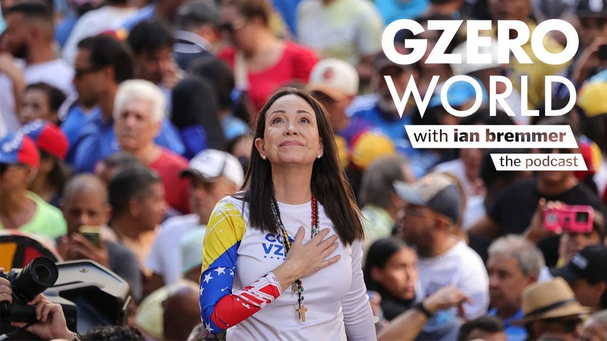 Venezuelan opposition leader María Corina Machado stands with her hand over her heart, looking upward during a rally, surrounded by a crowd of supporters. Text art reads "GZERO World with Ian Bremmer – the podcast."