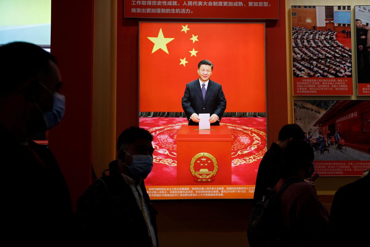 Visitors walk past an image of President Xi Jinping holding a ballot ahead of the 20th National Congress of the Communist Party of China in Beijing.