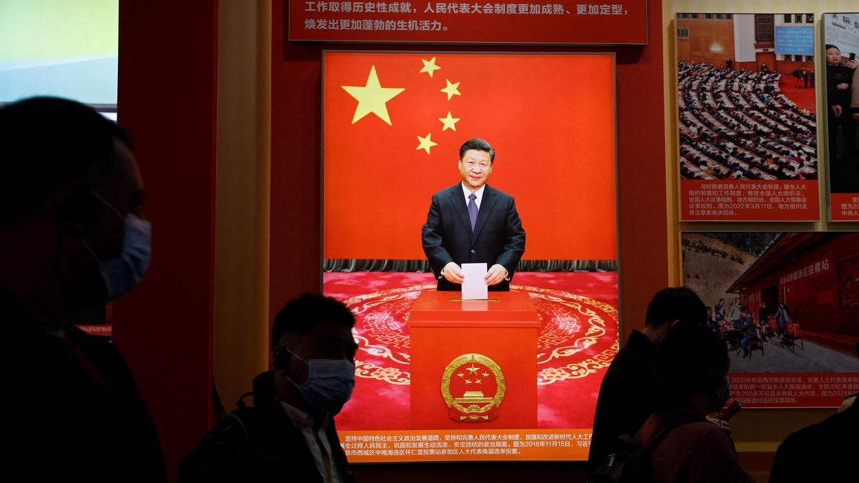 Visitors walk past an image of President Xi Jinping holding a ballot ahead of the 20th National Congress of the Communist Party of China in Beijing.