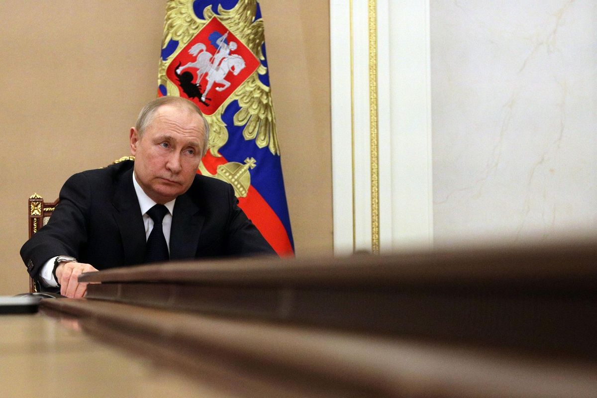 Vladimir Putin sits at the head of a conference table