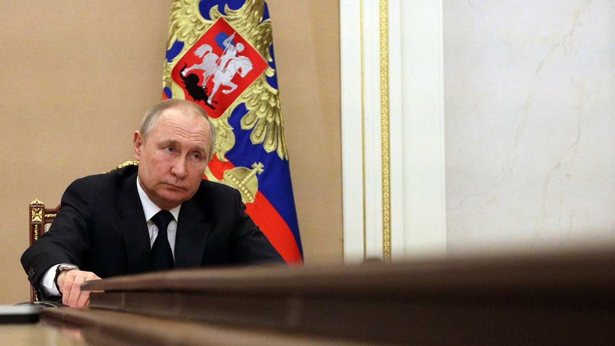 Vladimir Putin sits at the head of a conference table